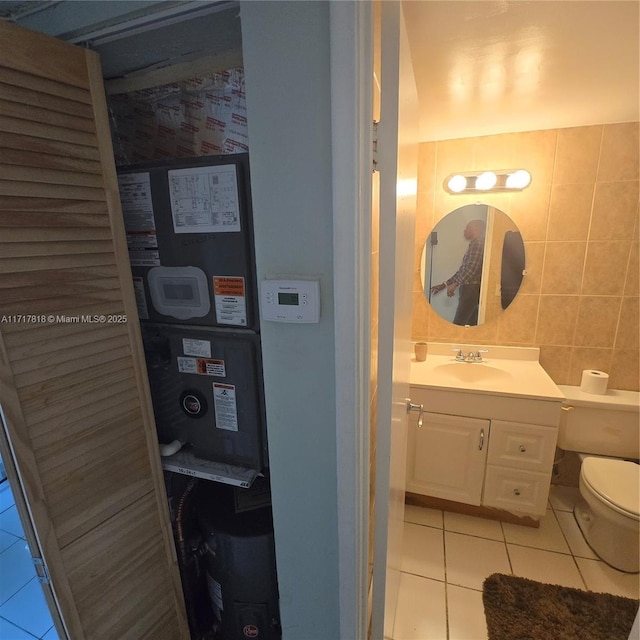 bathroom with tile patterned floors, vanity, toilet, and tile walls