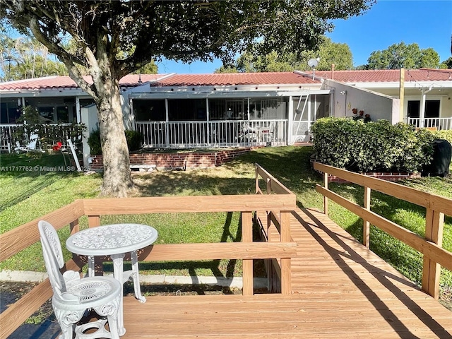 back of house featuring a lawn, a sunroom, and a wooden deck