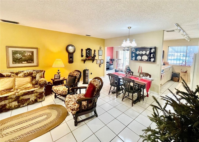 dining space featuring a wealth of natural light, light tile patterned floors, track lighting, and a notable chandelier