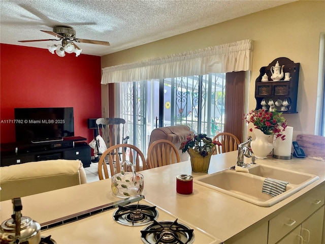 dining space featuring ceiling fan, sink, and a textured ceiling