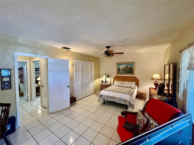 bedroom featuring ceiling fan, a closet, light tile patterned flooring, and a textured ceiling