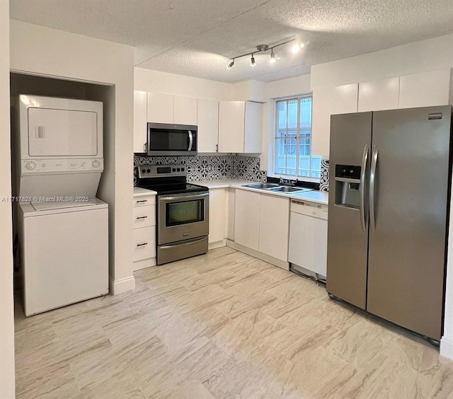 kitchen with sink, stainless steel appliances, tasteful backsplash, stacked washer / dryer, and white cabinets