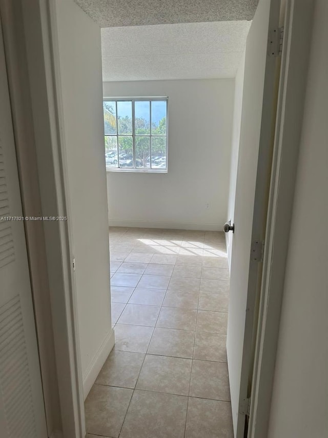 hallway with light tile patterned flooring and a textured ceiling