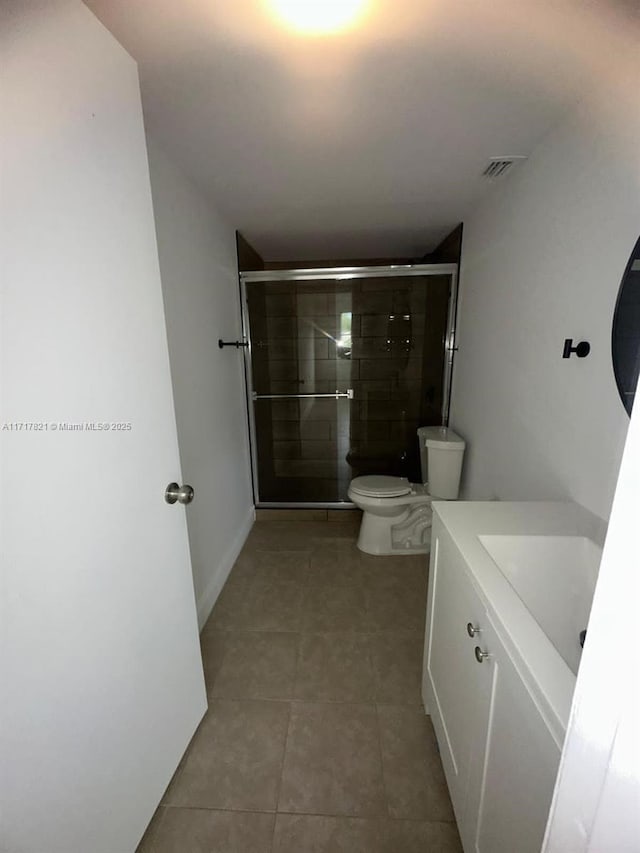 bathroom featuring tile patterned floors, vanity, an enclosed shower, and toilet