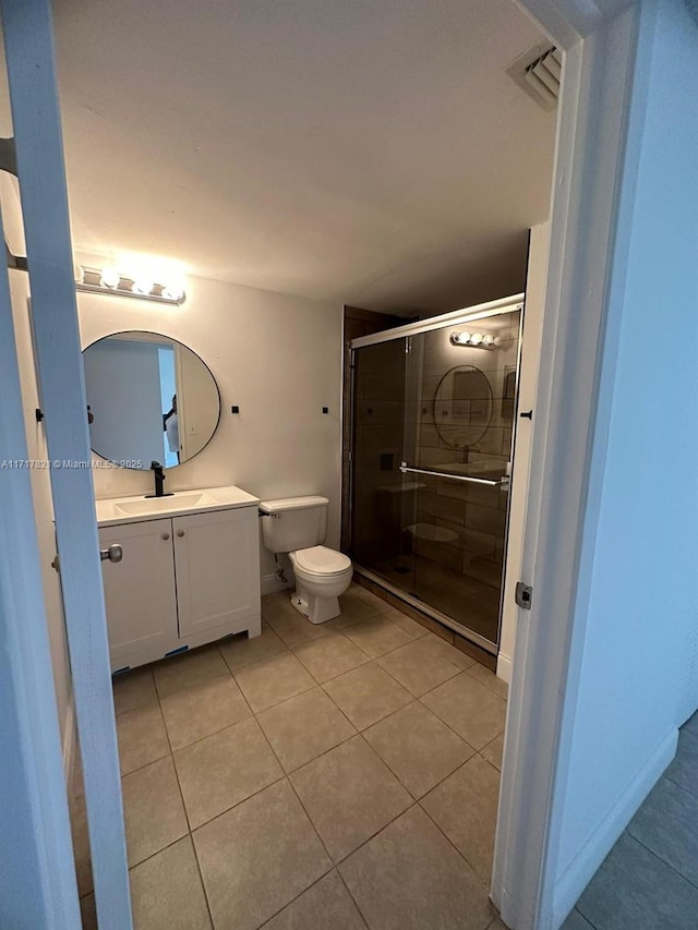 bathroom with tile patterned flooring, vanity, toilet, and a shower with shower door