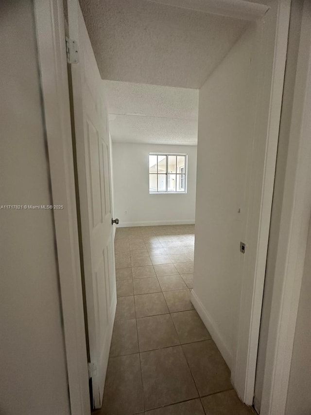 hallway with tile patterned floors and a textured ceiling