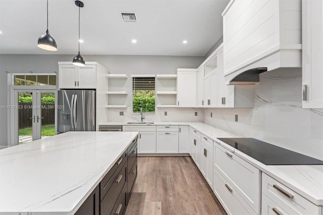 kitchen with white cabinets, stainless steel fridge, light stone countertops, and sink