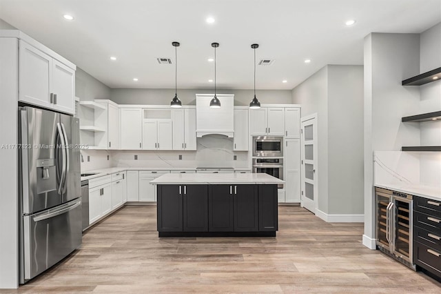 kitchen featuring appliances with stainless steel finishes, decorative light fixtures, white cabinets, a center island, and wine cooler