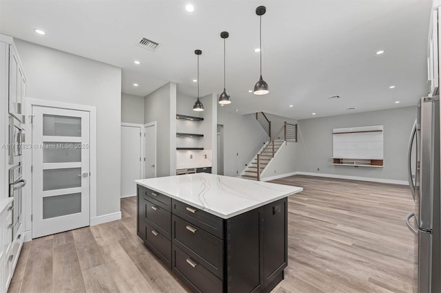 kitchen with white cabinets, appliances with stainless steel finishes, a kitchen island, and pendant lighting