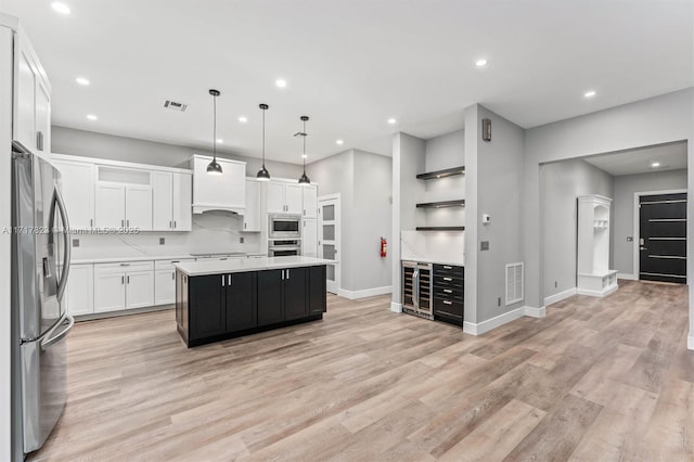 kitchen with a center island, decorative light fixtures, decorative backsplash, white cabinets, and appliances with stainless steel finishes