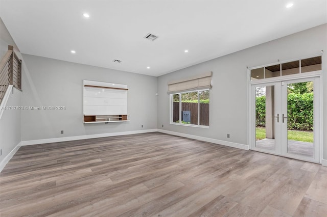 spare room with a healthy amount of sunlight, french doors, and light hardwood / wood-style flooring