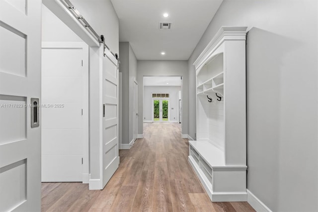 mudroom with a barn door and light hardwood / wood-style flooring