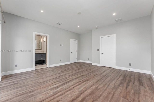 unfurnished bedroom with ensuite bath and light wood-type flooring