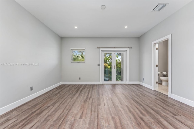 empty room featuring french doors and light hardwood / wood-style flooring