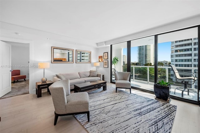 living area featuring a view of city, a wall of windows, and light wood-style flooring