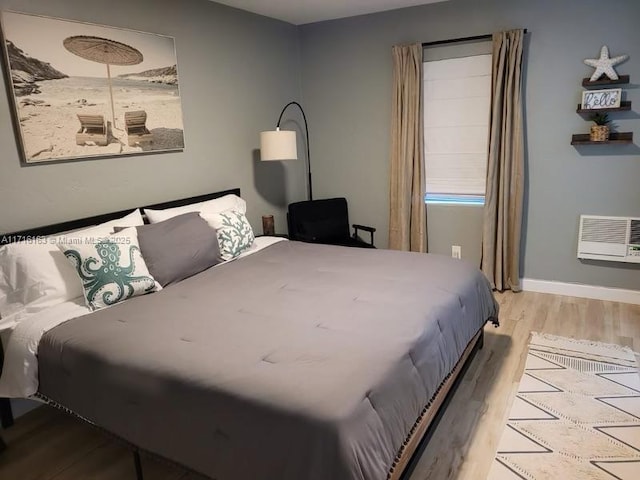 bedroom featuring a wall unit AC and light wood-type flooring