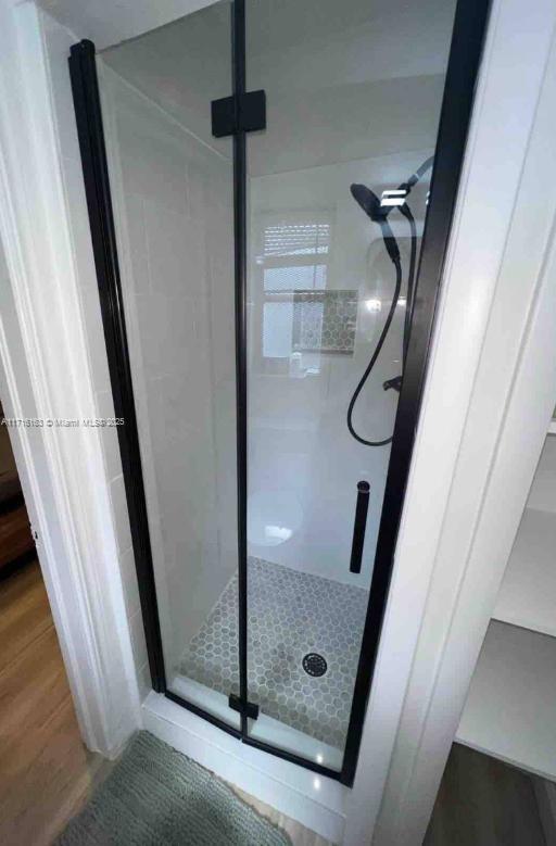 bathroom featuring a shower with door and wood-type flooring