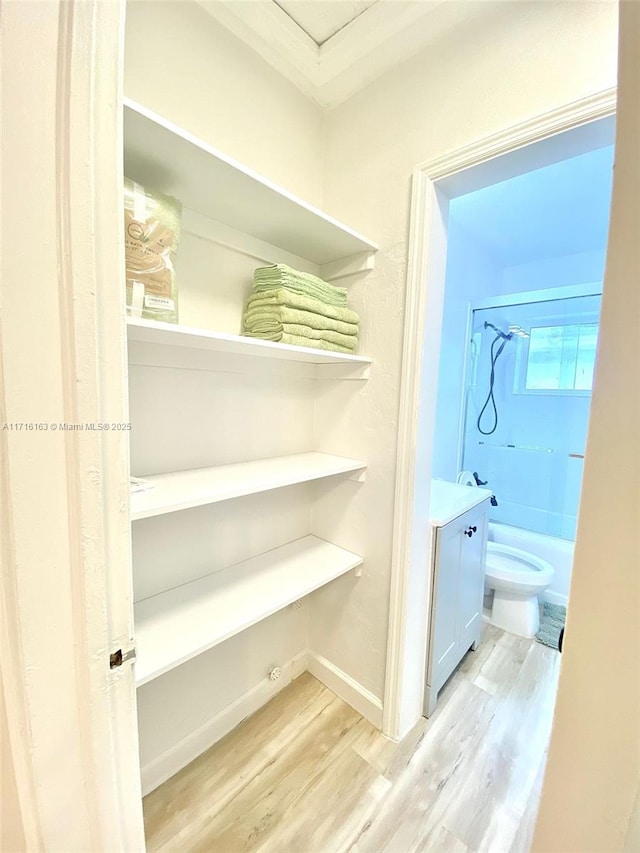 full bathroom with ornamental molding, bathtub / shower combination, vanity, hardwood / wood-style flooring, and toilet