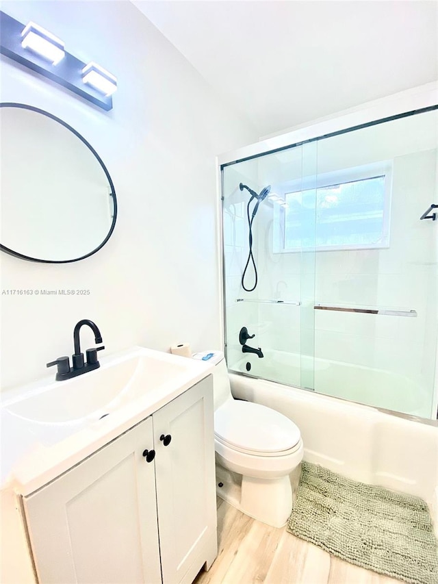 full bathroom featuring shower / bath combination with glass door, wood-type flooring, vanity, and toilet