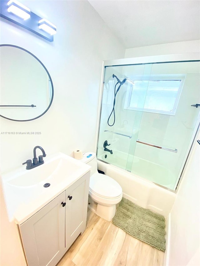 full bathroom with toilet, vanity, bath / shower combo with glass door, and hardwood / wood-style flooring