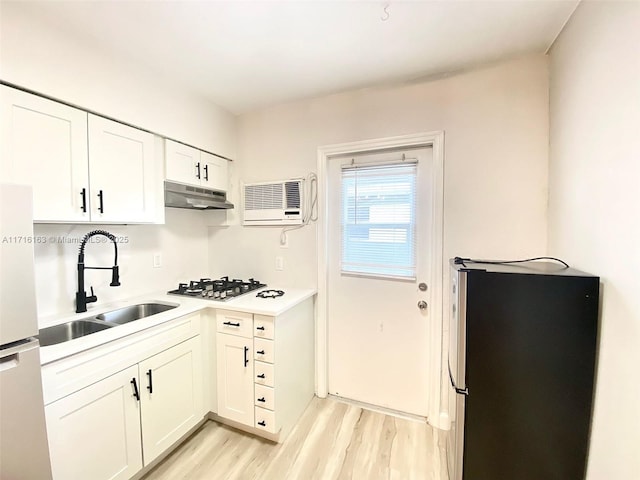 kitchen featuring stainless steel refrigerator, white cabinetry, sink, gas cooktop, and light hardwood / wood-style flooring