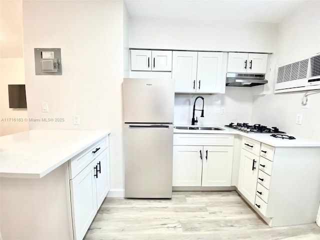 kitchen with sink, stainless steel fridge, light wood-type flooring, white cabinetry, and kitchen peninsula