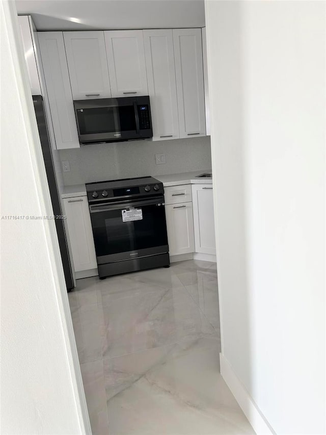 kitchen with black electric range oven, white cabinetry, and tasteful backsplash