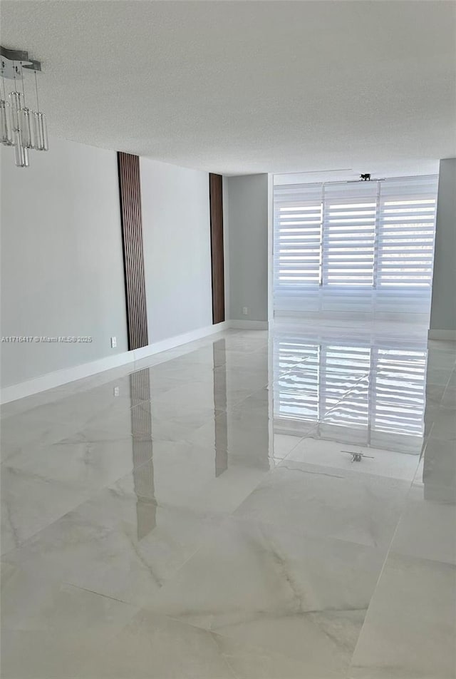 spare room with a textured ceiling and marble finish floor