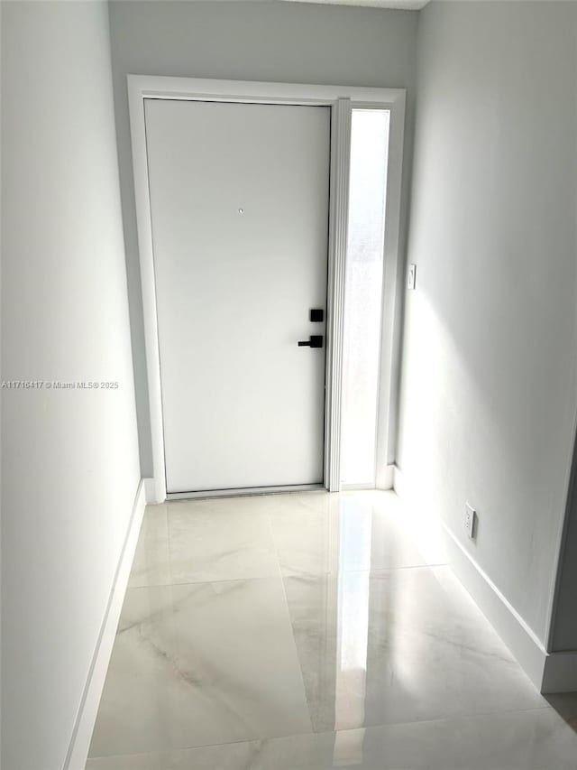 hallway with marble finish floor and baseboards