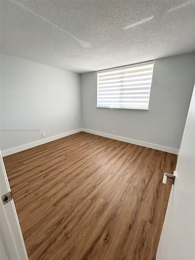 spare room featuring wood-type flooring and a textured ceiling