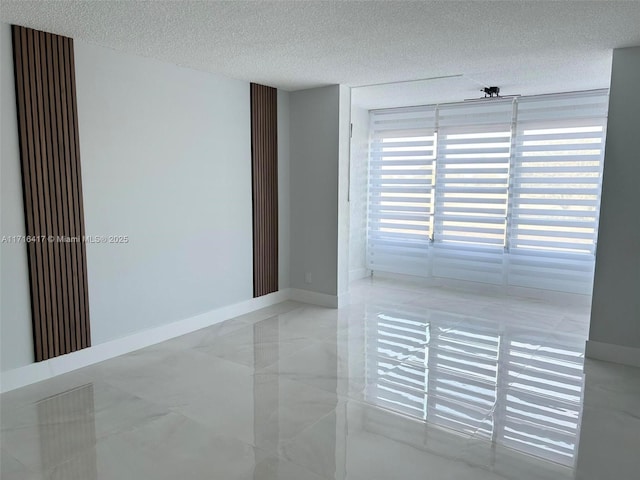 unfurnished room with a textured ceiling and baseboards