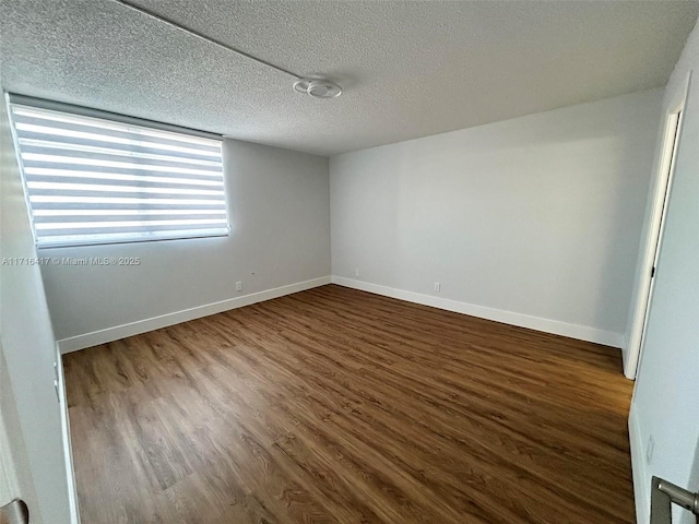 spare room featuring a textured ceiling and dark wood-type flooring