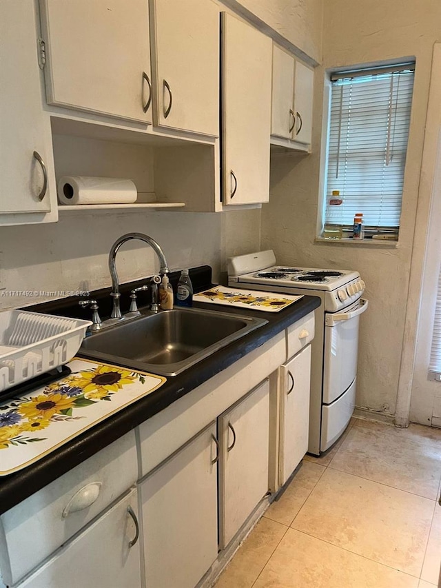 kitchen featuring white cabinetry, light tile patterned flooring, white gas range, and sink