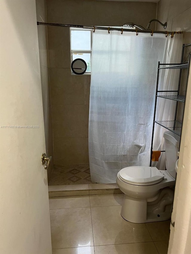 bathroom with tile patterned flooring, a shower with curtain, and toilet