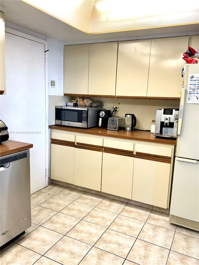 kitchen with butcher block counters, light tile patterned flooring, and stainless steel appliances