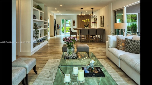 living room featuring built in features, hardwood / wood-style floors, and an inviting chandelier