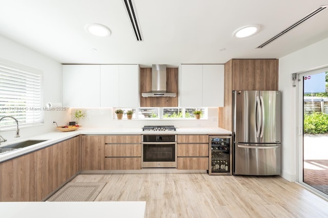 kitchen featuring sink, wall chimney exhaust hood, stainless steel appliances, beverage cooler, and white cabinets