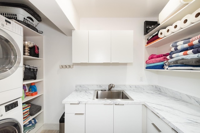 laundry room with cabinets, stacked washing maching and dryer, and sink