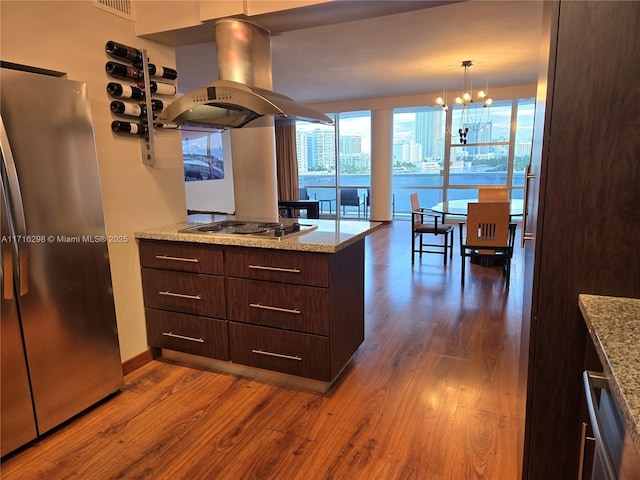 kitchen featuring hardwood / wood-style floors, pendant lighting, stainless steel fridge, dark brown cabinets, and island exhaust hood