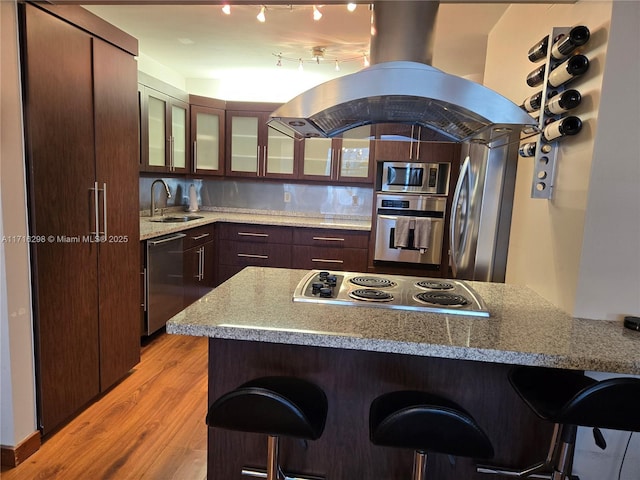 kitchen with a kitchen breakfast bar, sink, light hardwood / wood-style flooring, and appliances with stainless steel finishes