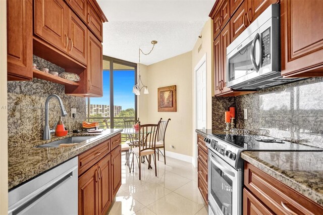 kitchen with pendant lighting, sink, light stone counters, stainless steel appliances, and a chandelier