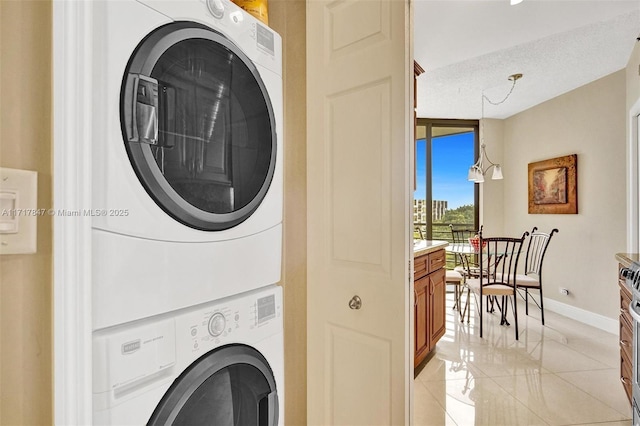 clothes washing area with a textured ceiling and stacked washer and clothes dryer