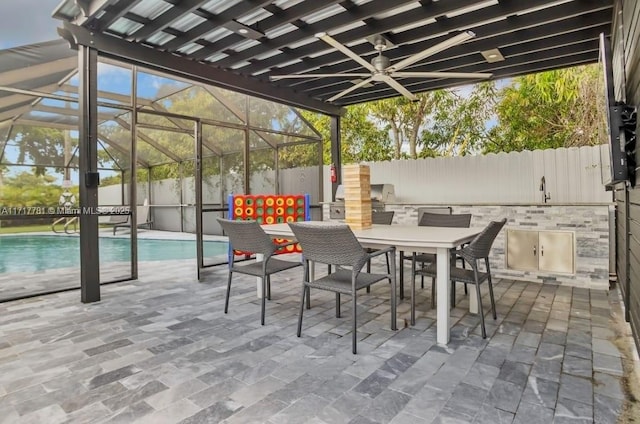 view of patio featuring a lanai, ceiling fan, exterior kitchen, and a fenced in pool