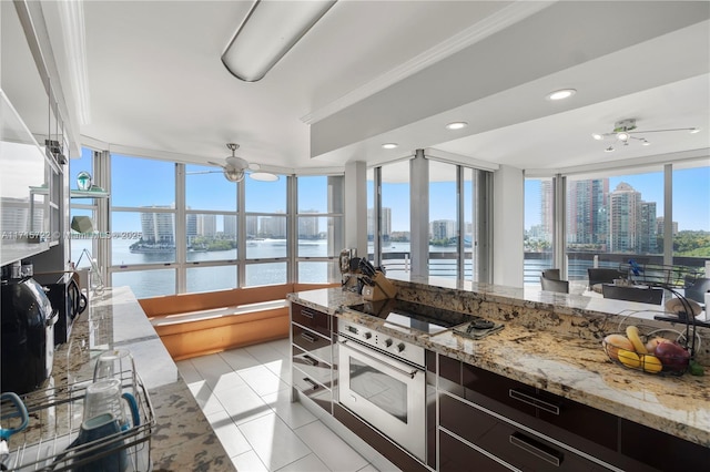 kitchen with light tile patterned floors, dark brown cabinetry, a water view, and a wealth of natural light