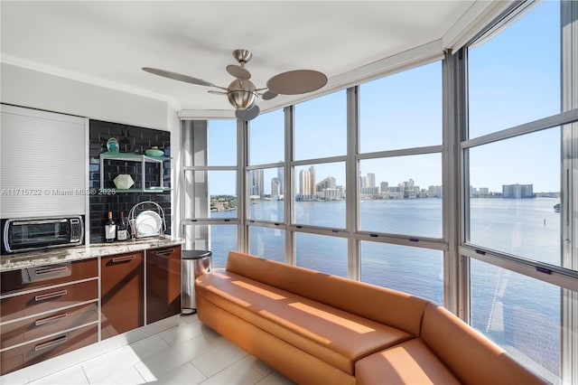 interior space with ceiling fan, a water view, light tile patterned floors, and a wealth of natural light