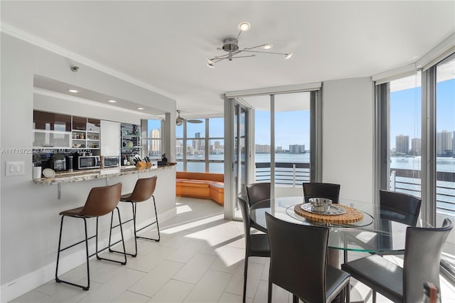 dining room with ceiling fan, a healthy amount of sunlight, a water view, and ornamental molding