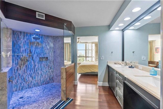 bathroom with hardwood / wood-style flooring, vanity, and tiled shower