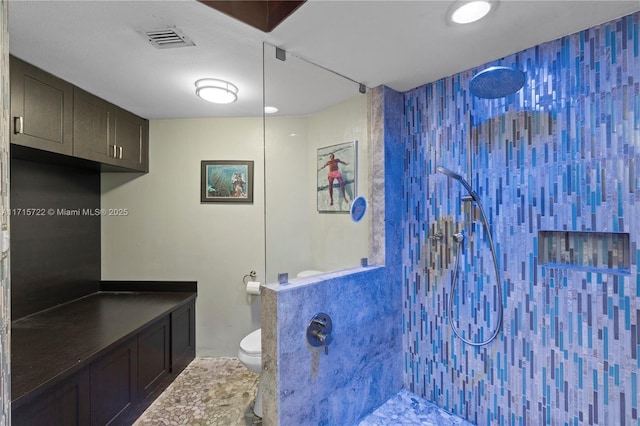 bathroom with tiled shower and toilet