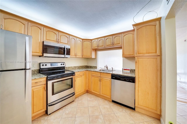 kitchen with light brown cabinets, stainless steel appliances, and sink