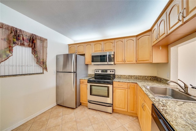 kitchen featuring appliances with stainless steel finishes, light brown cabinets, light tile patterned floors, and sink